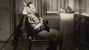 Den som har tandproblem ska inte vänta med att söka vård på grund av rädsla för coronaviruset, uppmanar Sari Holmberg. Lavastettu kuva 1920-1930-luvulta, jossa nainen istuu tuolissa ja kärsii hammassärystä.