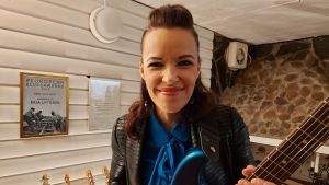 Med bluespris i bakgrunden. Erja Lyytinen med gitarr, i bakgrunden hennes pristavla för bästa europeiska bluesgitarrist