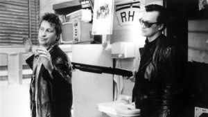 Väänänen tukalassa paikassa, haulikon toisessa päässä Wim Wenders. Taksikuski Alex (Kari Väänänen) uhattuna. Haulikkoa pitelee ohjaaja Wim Wenders elokuvassa Helsinki Napoli All Night Long.