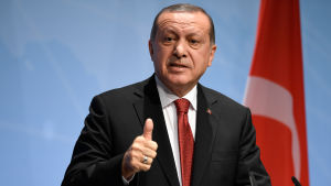 Turkiets president Recep Tayyip Erdoğan. Recep Tayyip Erdogan håller tal framför en Turkiet-flagga.