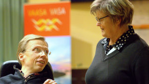 Johan Kullas i samspråk med Anita Niemi-Iilahti. Johan Kullas och Anita Niemi-Iilahti i fullmäktige.