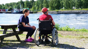 Också personer i rullstol ska kunna ta sig till stranden, anser nämnden. En äldre person vid flodstranden tillsammans med en yngre person.