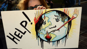 Många har demonstrerat inför klimatmötet, för att visa sitt stöd till de politiker som ska ta besluten. En kvinna håller upp en skylt med en svettig jordglod på, på en demonstration.