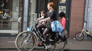 Cyklisten ska hålla sig på gatan eller på cykelvägen. En kvinna och ett barn cyklar. Ett mindre barn sitter på pakethållaren.