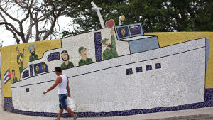En man passerar ett mosaikarbete i Havanna som visar Che Guevara, Raúl och Fidel Castro. Lördagen 16.4. En man passerar ett mosaikarbete i Havanna som visar Che Guevara, Raúl och Fidel Castro. Lördagen 16.4.2016