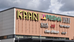 Yritysten nimiä valomainoksina. Kauppakeskus Kaari Helsingin Kannelmäessä. Valomainoksia kauppakeskuksen julkisivussa: Kaari (logo, liike merkki), Prisma, Sokos, K ylä-ravintola, H&M (Hennes ja Mauritz), Top-Sport, Clas Ohlson ja Aleksi13. Ostoskeskus, mainoksia, ni mikilpiä. Asiasa
