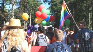 Flaggor, ballonger och många människor i prideparaden i Hangö.