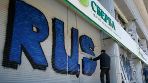 En ukrainsk arbetare tvättar bort graffiti från ryska statsägda Sberbanks vägg i Kiev i slutet av mars 2017. En arbetare i Ukraina tvättar bort graffiti från ryska statsägda Sberbanks vägg i Kiev i slutet av mars 2017.