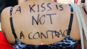 En kvinna demonstrerar mot våldtäkt med texten "en kyss är inget kontrakt".