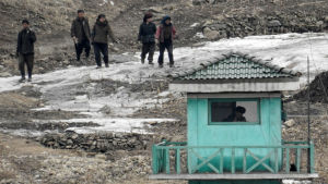 Bild tagen den 7 mars 2016 från den kinesiska staden Dangdong, som gränsar till Nordkorea. På bilden går nordkoreaner förbi en vakt. Bild tagen den 7 mars 2016 från den kinesiska staden Dangdong, som gränsar till Nordkorea. På bilden går nordkoreaner förbi en vakt.