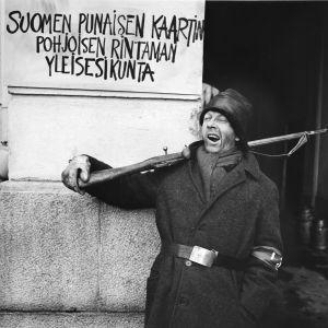 Tunnistamaton näyttelijä. Seinässä teksti "Suomen punaisen kaartin Pohjoisen rintaman yleisesikunta" tv-draamassa Lennu (1967).