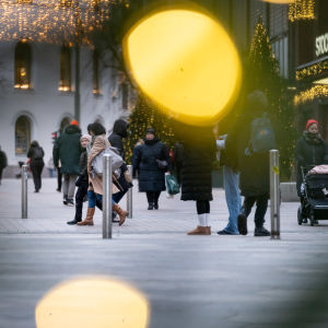 People and Christmas lights on a snowless street in central Helsinki.