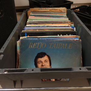 Tangokungen Reijo Taipale följer med Ströhös loppis ur en låda. LP-skivor i en låda i Strömborgska skolans musiksal.