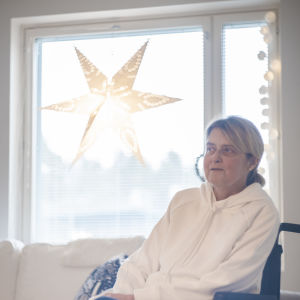 Tuija Wahalahti är frustrerad och trött på att hon inte fått tag på flera assistenter, och att Esbo stad inte hjälpt henne. "Det tär både på min fysiska och psykiska ork", säger hon. En kvinna sitter i en rullstol framför ett fönster. Hon ser åt sidan.
