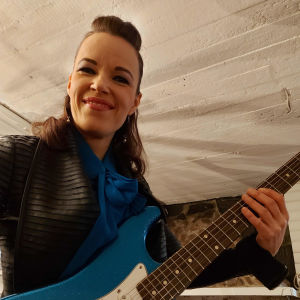 Man måste klä upp sig för blues, menar Lyytinen. Erja Lyytinen fotat nedrifrån, med gitarr. Ser leende in i kameran.