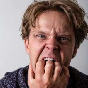 en ung man med ilsken blick biter på sina fingrar