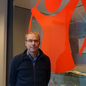 Max Holm har besökt Burkina Faso och träffat barn som Rädda Barnen har hjälpt. Foto på Max Holm som poserar intill Rädda Barnens röda logotyp