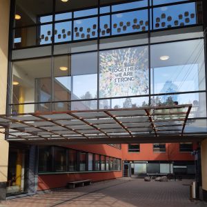Sammanhållning och samarbete mellan elever, lärare och vårdnadshavare utmanas av coronoviruspandemin. Granhultsskolans byggnad i glas och betong med texten Together we are strong skriven av elever på ett av fönstren.