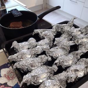 Den här kvällen blir det ugnspotatis som barnen har önskat sig. Potatis i folie på en ugnsplåt i köket. Intill en stekpanna med en biff i.