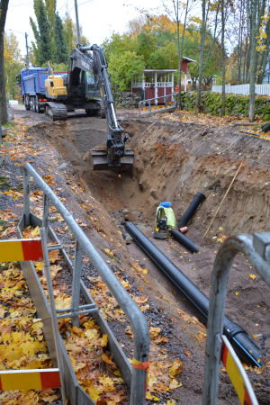Vattenrören är på plats vid Pastor Viréns park och täcks med sand. Grävskopa gräver ner vattenrör.