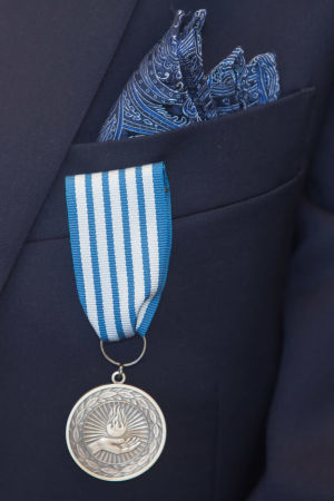 Livräddningsmedaljen har delats ut i Finland sedan 1920-talet. En silverfärgad medalj i ett blåvitt band som är fäst vid bröstfickan på en kavaj.
