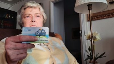 Äldre kvinna som håller i Esbo stads färdtjänstkort.