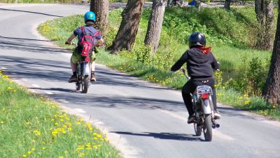 Mopedister kör efter varandra på en asfalterad väg.