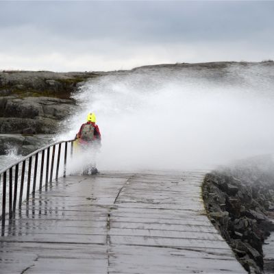 Kvinna tar sig över vågbrytare vid Ugnsholmen i Helsingfors