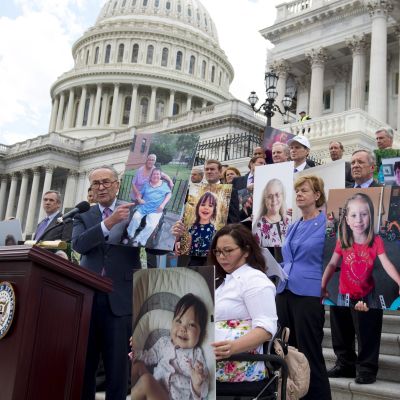 Minoritetsledaren och demokraten Chuck Schumer håller upp bilder på människor som skulle förlora sin sjukvårdsförsäkring republikanernas nya sjukvårdsförsäkring, vid en presskonferens utanför den amerikanska kongressen den 27 juni 2017. 