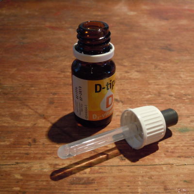 D-vitamindroppar i brun flaska på brunt bord.