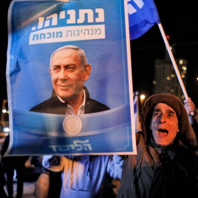 En man håller i en valplansch med ett foto på Israels premiärminister Benjamin Netanyahus  ropar slagord