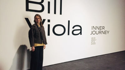 Kvinna framför vit vägg med texten Bill Viola.