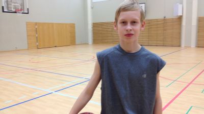 Oscar Storgård stor i en gymnastiksal med en basketboll under armen. 