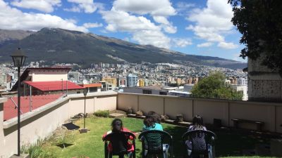 Utsikt från taket på en skola i Ecuador. I bakgrunden reser sig berg mot en blå himmel.