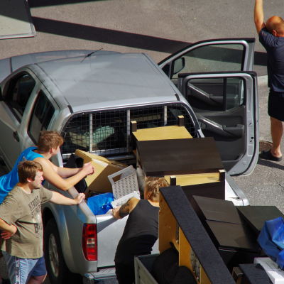 En grupp personer lastar möbler från en släpkärra.