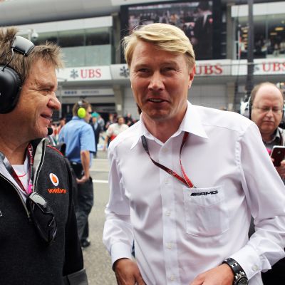 McLarenin lääkäri Aki Hintsa ja Mika Häkkinen hymyilevät F1-varikolla vuonna 2012.