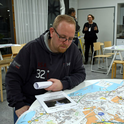 En man sitter vid ett runt bord och studerar en karta.