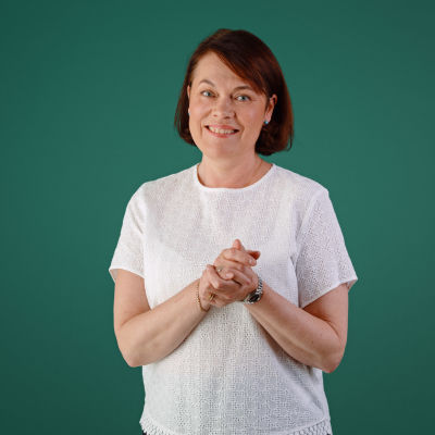 Martina Harms-Aalto står mot en grön bakgrund och småler mot kameran.