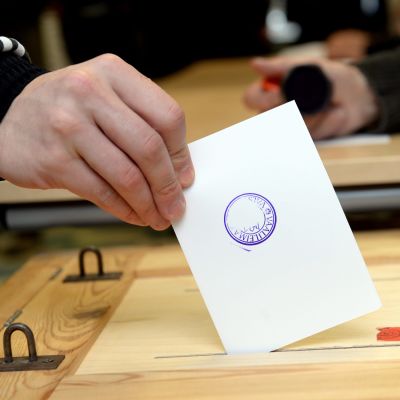 En person sätter röstsedeln i valurnan.