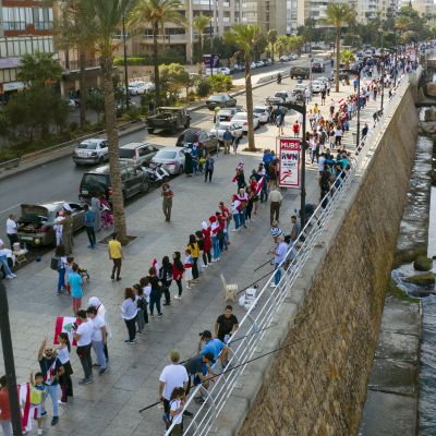 Människor står vid en gata i Beirut och formar kedja genom att hålla varandra i händerna.
