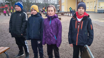 Fyra skolelever poserar på en skolgård.