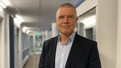 Man i skjorta och kavaj står i en korridor.
