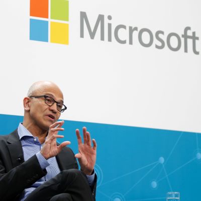 I förgrunden vd Satya Nadella, och upptill Microsofts logo.