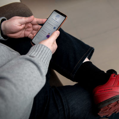En person sitter med Coronablinkern öppen i en mobiltelefon.  