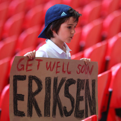 En pojke håller upp en skylt med texten "Get well soon Eriksen" där han står på läktaren under matchen mellan England och Krotatien.
