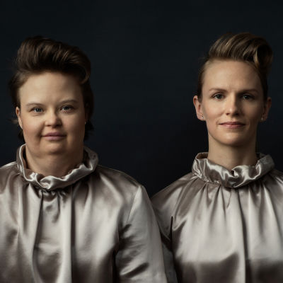 Skådespelarna Karolina Karanen och Sophia Heikkilä står i silverfärgade dräkter och ser rakt in i kameran.