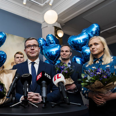 Samlingspartiets ledande politiker bland blå hjärtformade ballonger.