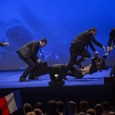 En aktivist bärs ut från scenen av Le Pens säkerhetsvakter.