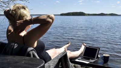 En kvinna sitter och jobbar vid en strand.