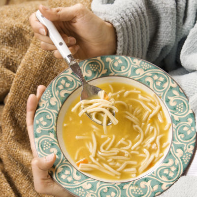 Person inbäddad i filt sitter med en tallrik soppa i famnen